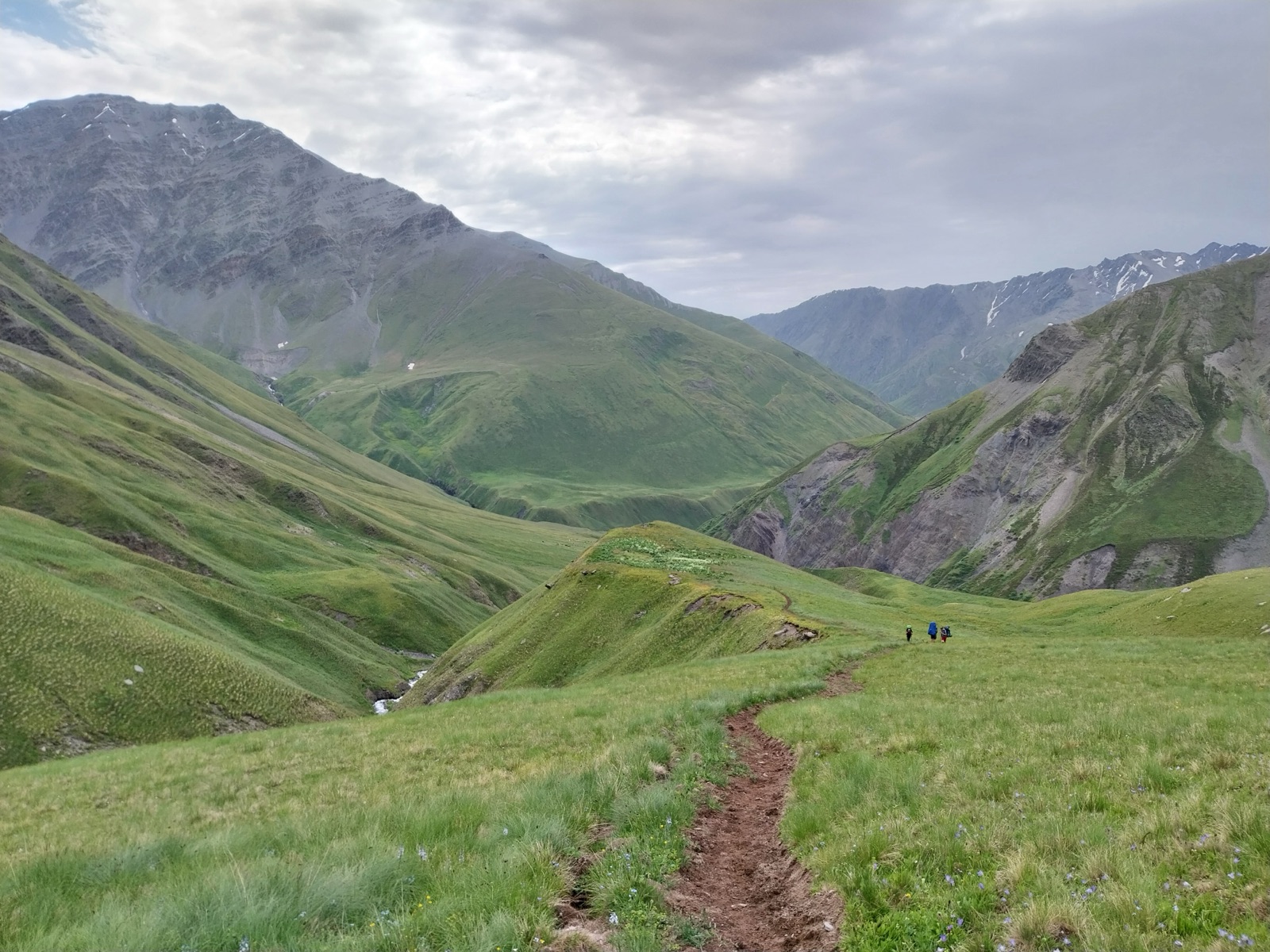 Hikers with backpacks climbing toward the Atsunta Pass in Tusheti