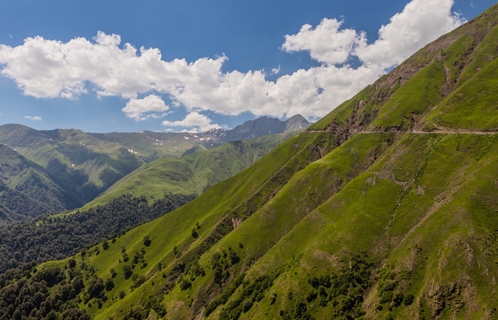 Carretera a Omalo tallada en una ladera verde de Tusheti en junio