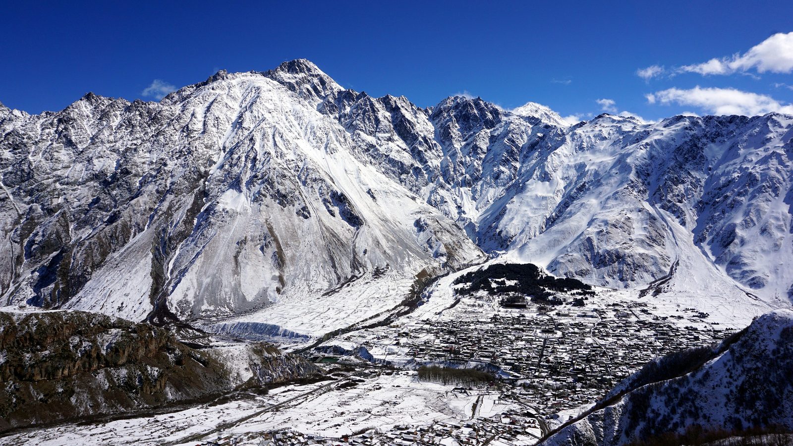 Snow-covered Stepantsminda beneath the mountain peaks in March